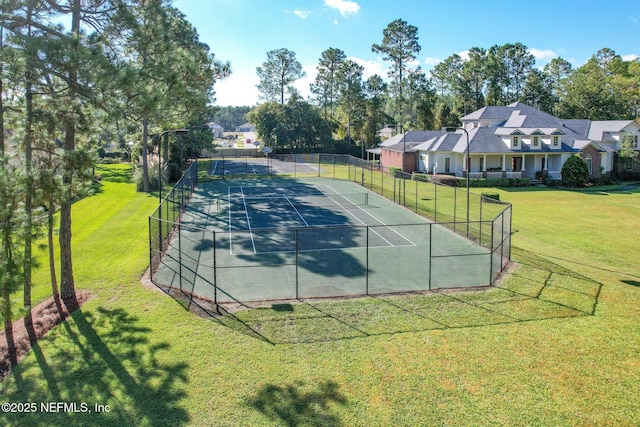 view of tennis court featuring a yard and fence