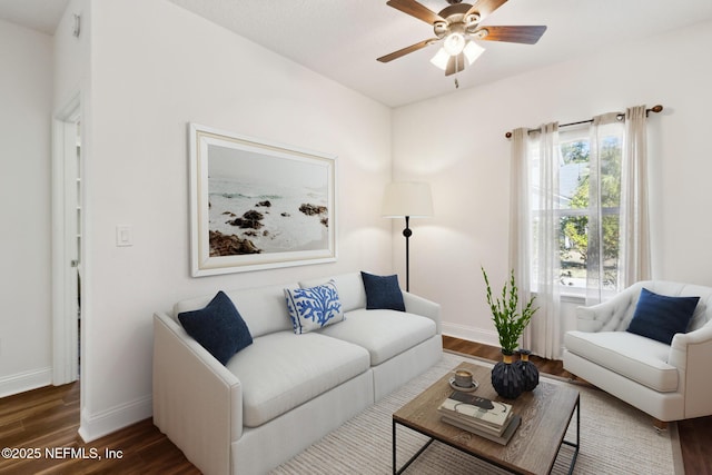 living room with dark wood-type flooring, ceiling fan, and baseboards