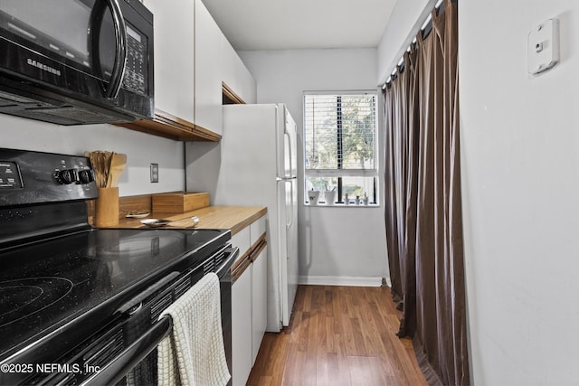 kitchen featuring baseboards, black appliances, dark wood-type flooring, light countertops, and white cabinetry