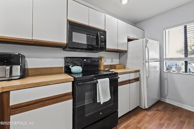 kitchen with black appliances, baseboards, butcher block countertops, white cabinetry, and dark wood-style flooring