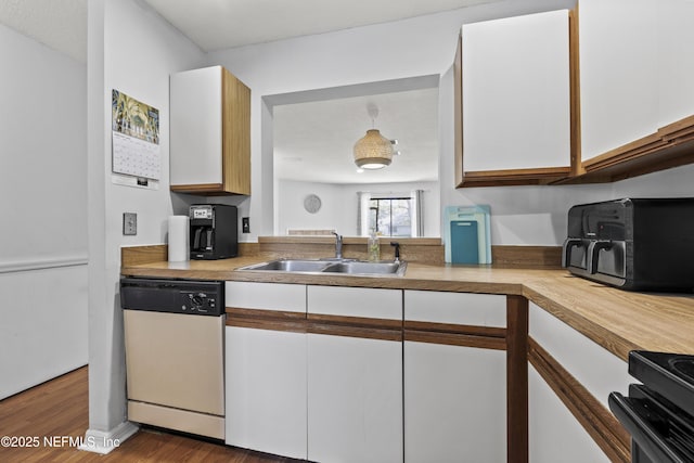 kitchen with a sink, wood finished floors, white cabinets, light countertops, and dishwasher