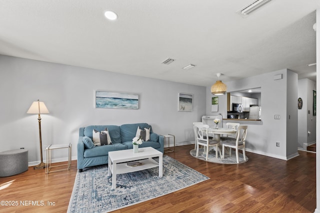 living area with visible vents, baseboards, and wood finished floors