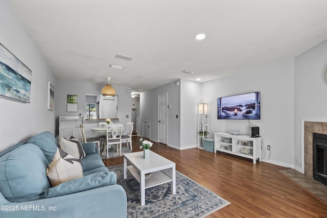 living area with recessed lighting, a fireplace, baseboards, and wood finished floors