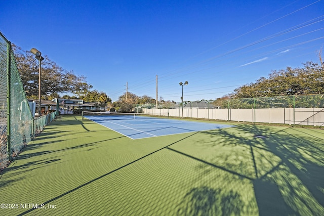 view of tennis court featuring fence