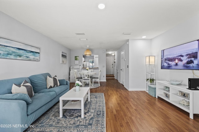 living room featuring visible vents, baseboards, and wood finished floors