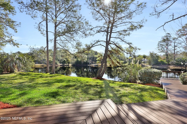 wooden deck with a water view and a lawn