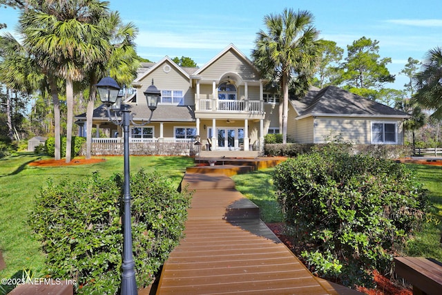 rear view of property featuring a yard and a balcony