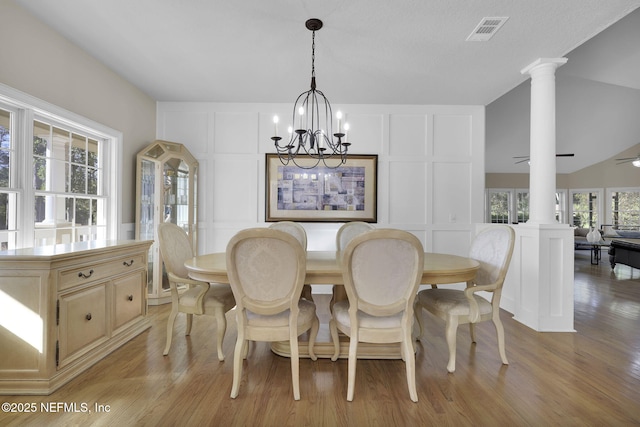 dining space with ornate columns, visible vents, a decorative wall, and light wood-style floors