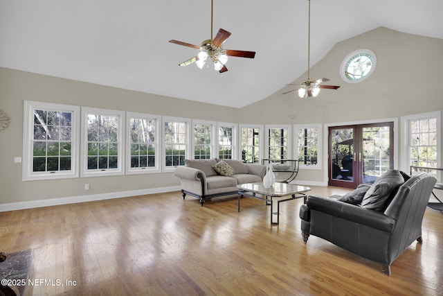 living room featuring light wood finished floors, high vaulted ceiling, french doors, and baseboards