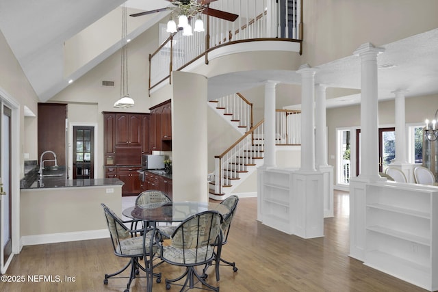 dining space featuring high vaulted ceiling, ornate columns, visible vents, and wood finished floors