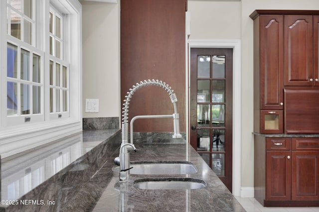 kitchen with a sink, dark stone countertops, and dark brown cabinets