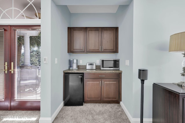 bar featuring freestanding refrigerator, french doors, stainless steel microwave, and a healthy amount of sunlight