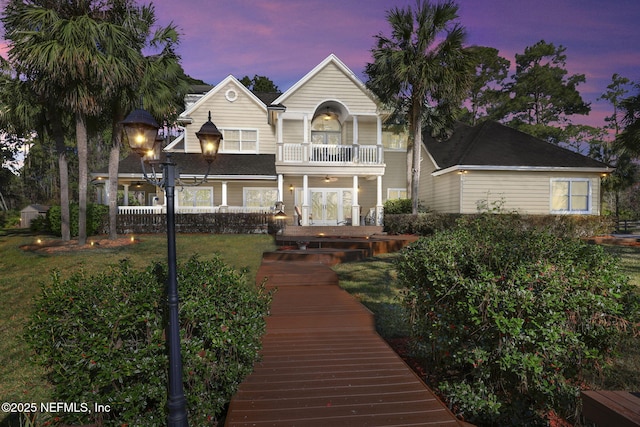 view of front of home featuring a balcony, fence, and a front yard