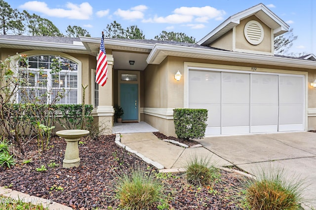 view of front of property featuring driveway, an attached garage, and stucco siding