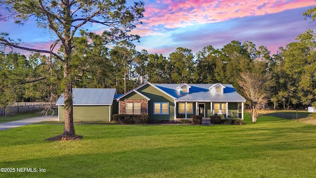 view of front of home with a front yard, covered porch, metal roof, and fence