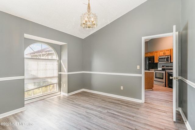 unfurnished dining area featuring baseboards, lofted ceiling, light wood-style floors, an inviting chandelier, and a textured ceiling