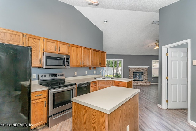 kitchen with open floor plan, light countertops, black appliances, a ceiling fan, and a sink