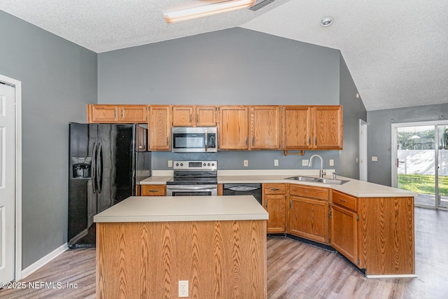 kitchen featuring black appliances, light wood-style flooring, a sink, a peninsula, and light countertops