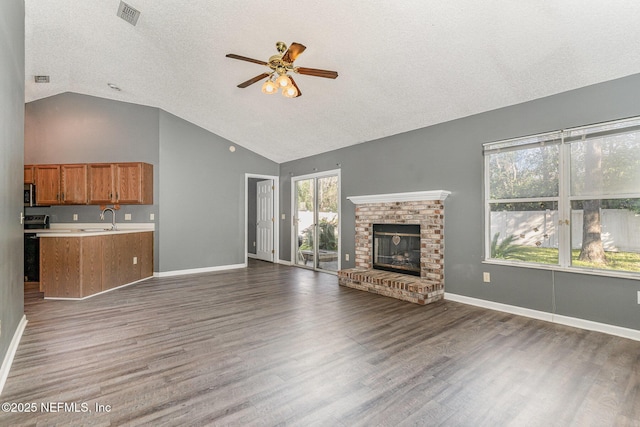 unfurnished living room with visible vents, a sink, wood finished floors, a fireplace, and ceiling fan