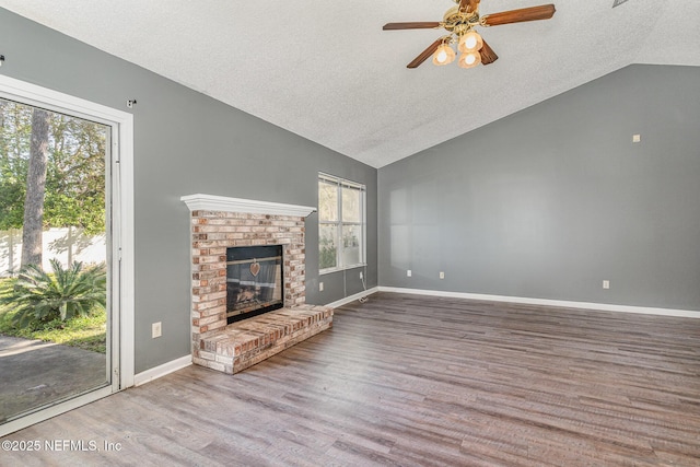 unfurnished living room with baseboards, lofted ceiling, a fireplace, wood finished floors, and a ceiling fan