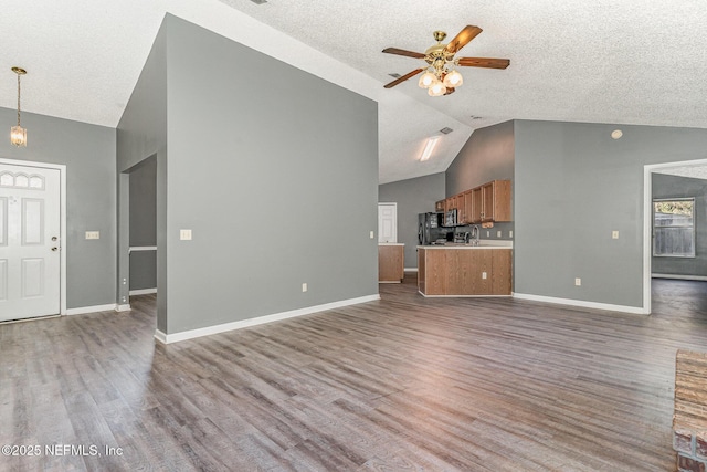 unfurnished living room featuring wood finished floors, baseboards, high vaulted ceiling, ceiling fan, and a textured ceiling