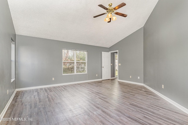 spare room featuring wood finished floors, a ceiling fan, baseboards, high vaulted ceiling, and a textured ceiling