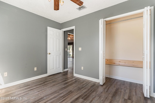 unfurnished bedroom with dark wood-style floors, visible vents, ceiling fan, and baseboards