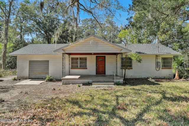 view of front facade featuring roof with shingles, a porch, a front yard, and a garage