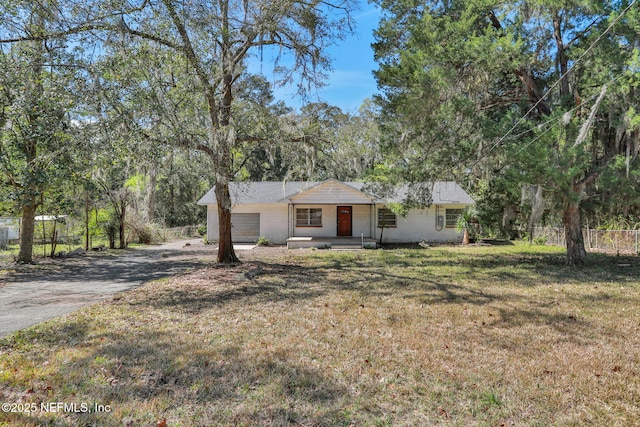 ranch-style house with an attached garage, fence, driveway, and a front lawn