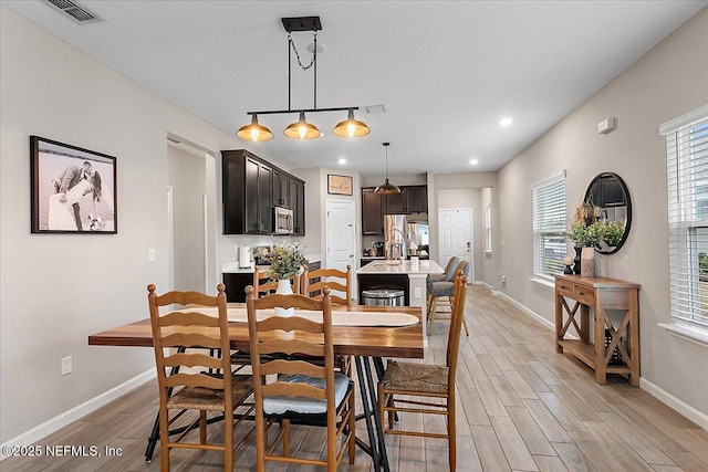 dining room with a textured ceiling, light wood-style flooring, recessed lighting, visible vents, and baseboards