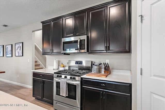 kitchen featuring wood finish floors, light countertops, visible vents, appliances with stainless steel finishes, and a textured ceiling