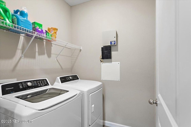 clothes washing area with laundry area, washing machine and dryer, and baseboards