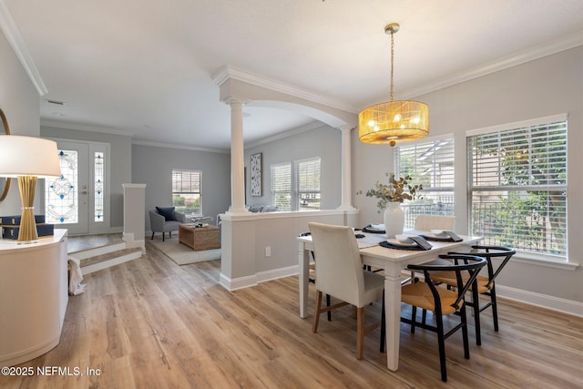 dining area featuring a chandelier, baseboards, ornamental molding, light wood-type flooring, and ornate columns