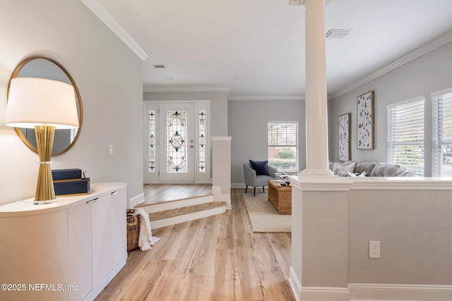 foyer entrance with visible vents, light wood-type flooring, decorative columns, and crown molding