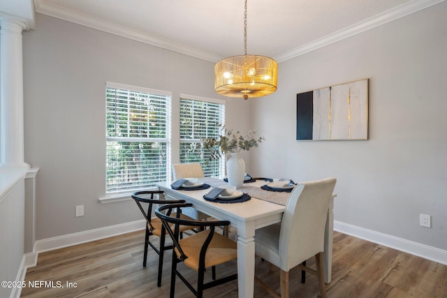 dining area with baseboards, wood finished floors, an inviting chandelier, crown molding, and ornate columns