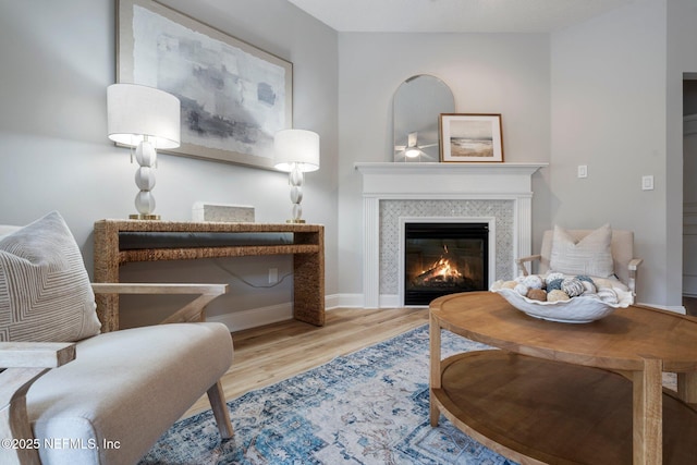 living area with baseboards, wood finished floors, and a glass covered fireplace