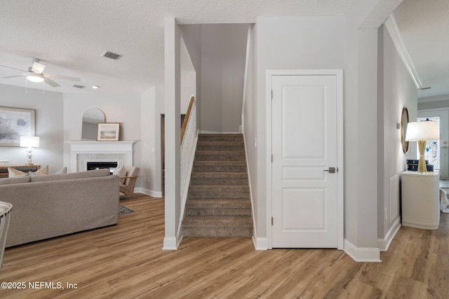 stairs featuring a textured ceiling, a fireplace, baseboards, and wood finished floors