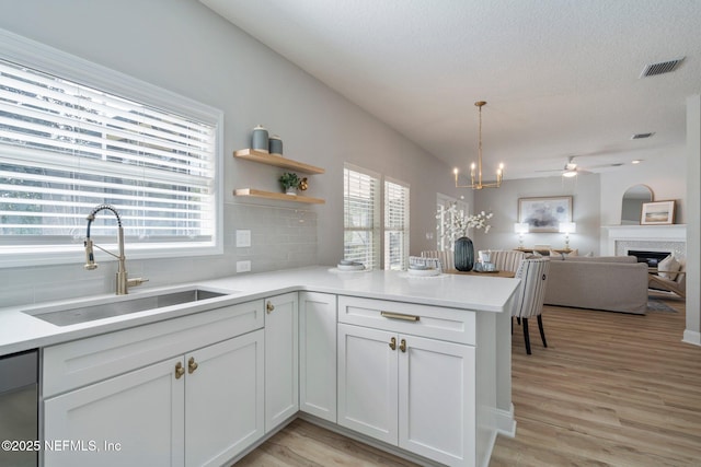 kitchen with light countertops, visible vents, light wood-style flooring, stainless steel dishwasher, and a sink