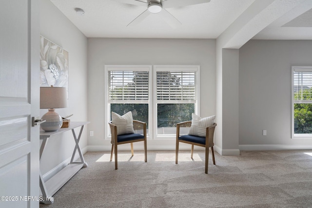 sitting room featuring a ceiling fan, baseboards, and carpet flooring