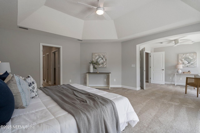 carpeted bedroom with baseboards, visible vents, a tray ceiling, and a ceiling fan