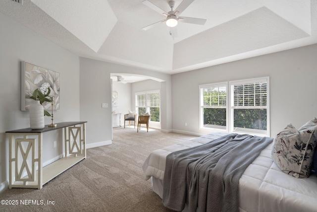 bedroom with arched walkways, a raised ceiling, light colored carpet, and baseboards