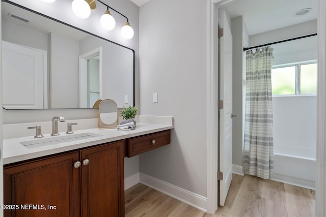 full bathroom with wood finished floors, vanity, visible vents, baseboards, and shower / bath combination with curtain