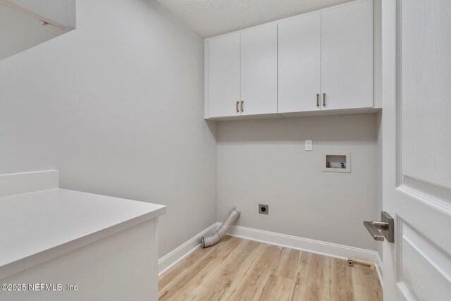 washroom featuring washer hookup, cabinet space, hookup for an electric dryer, light wood-type flooring, and baseboards