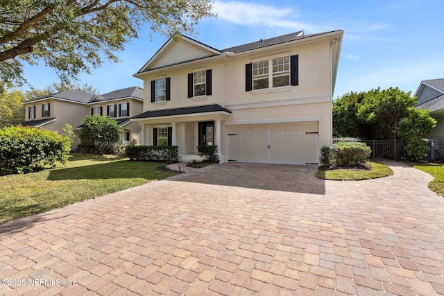 view of front of home featuring a garage, fence, decorative driveway, stucco siding, and a front lawn