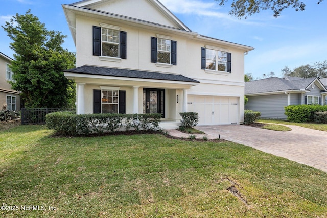 traditional-style house featuring an attached garage, fence, decorative driveway, a front lawn, and stucco siding