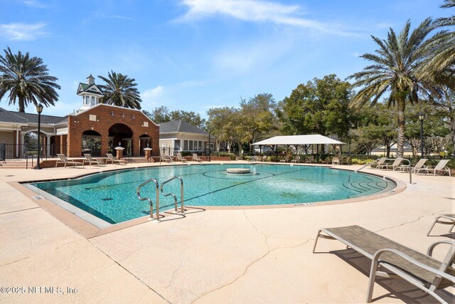 community pool with a patio area and fence