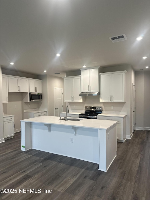 kitchen with appliances with stainless steel finishes, a center island with sink, dark hardwood / wood-style flooring, sink, and white cabinetry