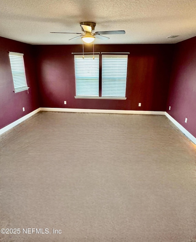 spare room with baseboards, visible vents, ceiling fan, and a textured ceiling