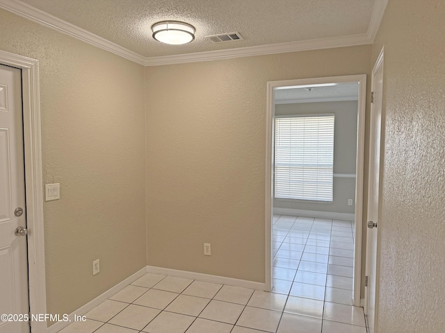 empty room featuring a textured ceiling, light tile patterned flooring, visible vents, and crown molding