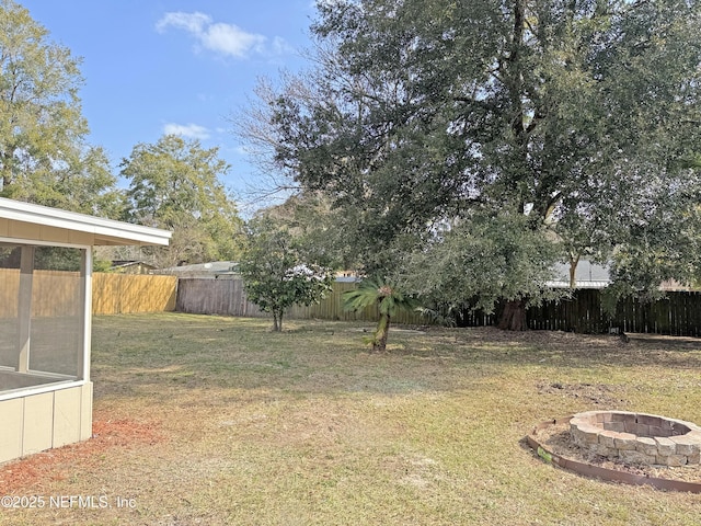 view of yard with a fenced backyard and a fire pit